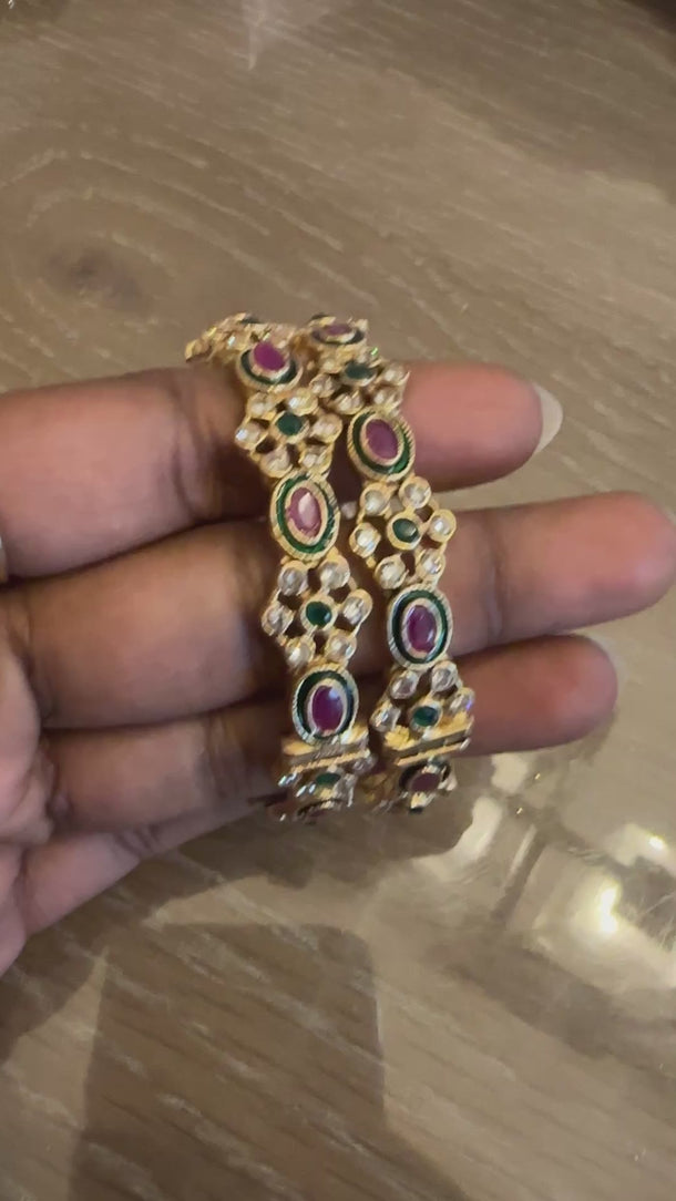 Video of kundan flower bangles with ruby and emerald accents in soft light